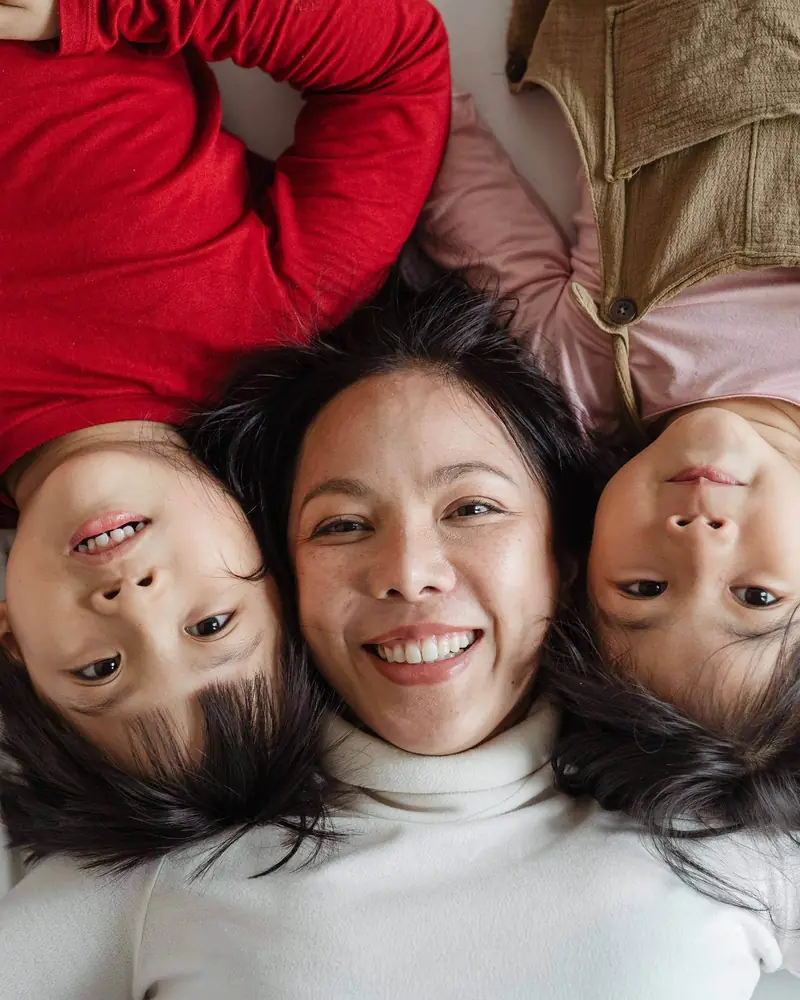 A mother lying on a bed with her two children