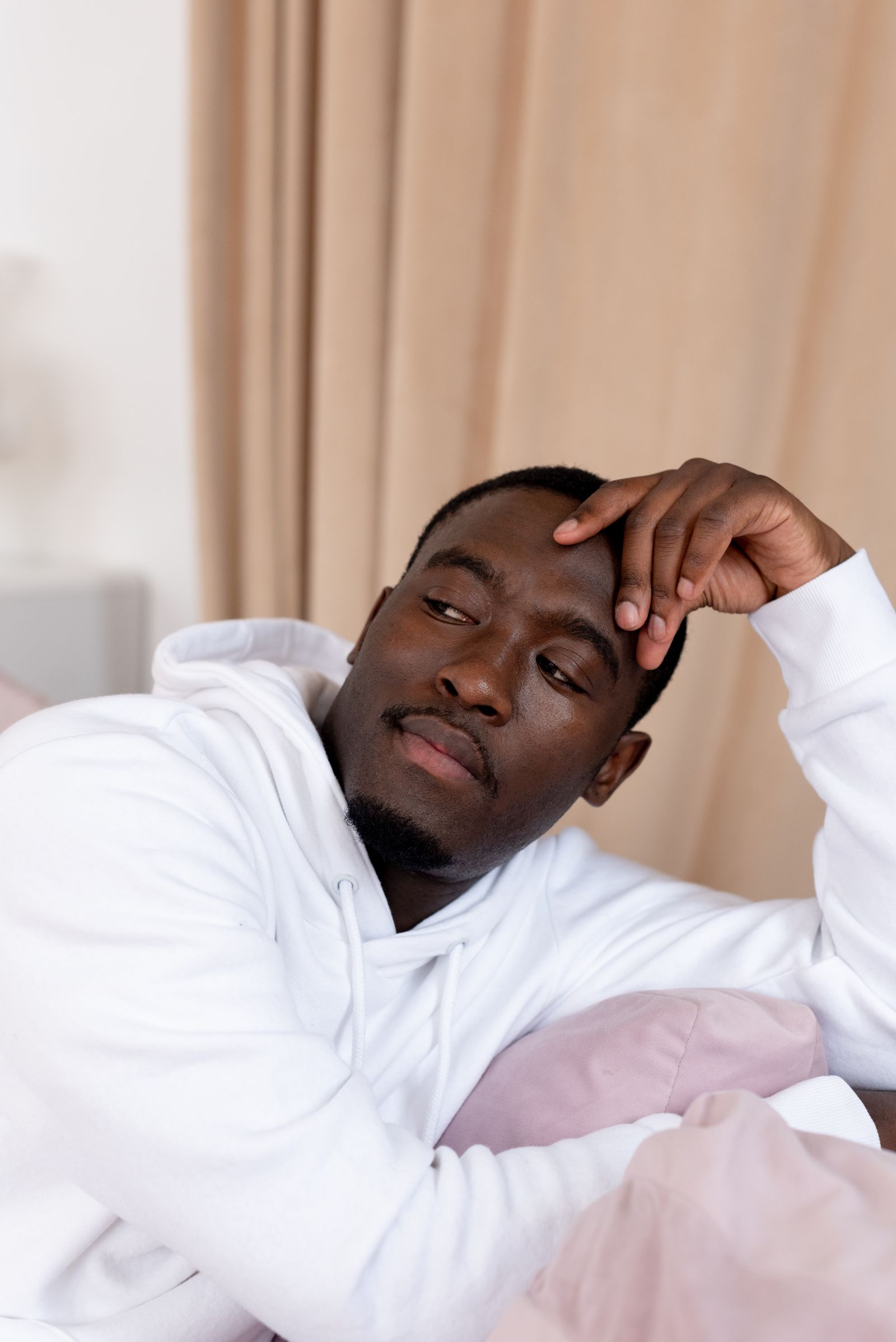 A man resting his head on his hand while sitting indoors