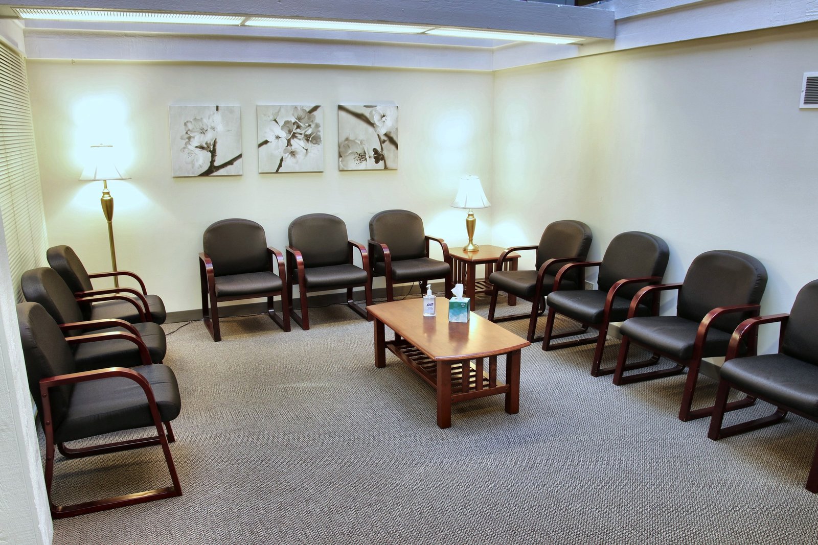 The waiting room at the Naperville office, with rows of dark chairs, a wooden coffee table, two lamps, and floral prints on the wall.