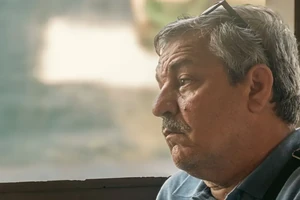 An older man looking quietly out a window.